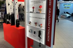 Ekspozycja targowa firmy CAREL przedstawia elektroniczne zawory rozprężne i urządzenia sterujące na szklanych półkach z etykietami produktów. Ekspozytor jest biały z czerwonymi akcentami i tekstem w języku polskim, umieszczony w jasno oświetlonej hali wystawowej. projekt i nadzór Tatjana Kobuszewska trksystem.com