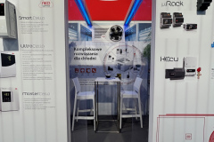 Stoisko targowe firmy CAREL z drzwiami z czerwonym logo nad nimi, prowadzące do małego stolika i krzeseł. Plakaty po obu stronach przedstawiają produkty do kontroli chłodzenia i chłodzenia, z polskim tekstem opisującym rozwiązania i nazwy produktów. projekt i nadzór Tatjana Kobuszewska trksystem.com