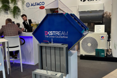 Stoisko targowe prezentuje logo Alfaco, Carel i Gree. Pośrodku prezentowany jest przemysłowy krzyżowo-przeciwprądowy wymiennik ciepła firmy 3KStream. Dwie osoby siedzą przy białej ladzie w tle; sprzęt HVAC i broszury są widoczne w pobliżu. projekt i nadzór Tatjana Kobuszewska trksystem.com