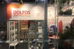 Stoisko targowe firmy DOLFOS PETS z produktami żywieniowymi na półkach, czerwono-białą ekspozycją, zielonymi roślinami i hasłem zasady prawidłowego żywienia na tylnej ścianie. projekt i nadzór Tatjana Kobuszewska trksystem.com