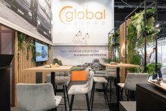 Stoisko targowe Global Motion w Ptak Warsaw Expo to stoły i krzesła, wiszące lampy, zieleń i napis Twój operator logistyczny dla branży automotive. projekt i nadzór Tatjana Kobuszewska trksystem.com