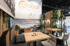 Nowoczesne stoisko targowe dla Stoiska targowego Global Motion na Ptak Warsaw Expo, z miejscami do siedzenia, wysokimi stołami, zielenią, banerami promocyjnymi i ekranem prezentującym usługi logistyczne. projekt i nadzór Tatjana Kobuszewska trksystem.com