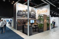 Stoisko targowe Global Motion w Ptak Warsaw Expo obejmuje ciężarówki na panelach wystawowych, zachęcające miejsca do siedzenia, zieleń i przechodzących gości. projekt i nadzór Tatjana Kobuszewska trksystem.com