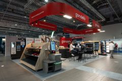 Stoisko targowe z brandingiem stoiska targowego Gondella, półkami ekspozycyjnymi, miejscem do siedzenia ze spotykającymi się ludźmi i czerwonymi znakami wewnątrz Hali EXPO XXI podczas targów Targi Retail Show. projekt i nadzór Tatjana Kobuszewska trksystem.com