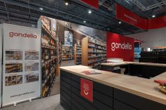 Stoisko targowe Gondella w Hali EXPO XXI, wyposażone w oznakowanie marki, baner prezentujący produkty oraz ladę z broszurami i kieliszkami do wina podczas targów Targi Retail Show. projekt i nadzór Tatjana Kobuszewska trksystem.com