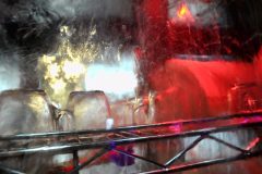 Widok z bliska na szklane naczynia i metalowy stojak wewnątrz zmywarki w Forum Szefów Kuchni i Restauratorów, z rozmytymi odbiciami i czerwonymi, żółtymi i białymi światłami. projekt i nadzór Tatjana Kobuszewska trksystem.com