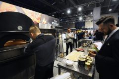 W tętniącym życiem Forum Szefów Kuchni i Restauratorów Expo XXI mężczyzna przygotowuje pizzę w dużym piecu, podczas gdy inny sprawdza składniki w puszkach na ladzie, prezentując najlepszy sprzęt firmy Hendi. projekt i nadzór Tatjana Kobuszewska trksystem.com