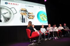 Sześć osób siedzi na scenie na czerwonych krzesłach podczas panelu dyskusyjnego w Forum Szefów Kuchni i Restauratorów, a za nimi wyświetlane jest logo Hendi i zdjęcia sprzętu gastronomicznego na Expo XXI. projekt i nadzór Tatjana Kobuszewska trksystem.com