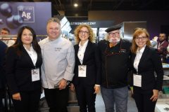 Pięć osób, trzy kobiety w strojach biznesowych i dwóch mężczyzn w strojach szefów kuchni, uśmiecha się do siebie podczas Forum Szefów Kuchni i Restauratorów w Expo XXI. projekt i nadzór Tatjana Kobuszewska trksystem.com