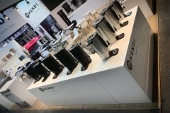 Stoisko targowe prezentuje kilka dużych czarnych i srebrnych dystrybutorów napojów na białych ladach z marką HENDI. Za stoiskiem ustawiono białe krzesła i stoły w nowoczesnym, dobrze oświetlonym otoczeniu. projekt i nadzór Tatjana Kobuszewska trksystem.com