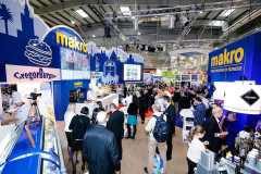 Na targach Targi Eurogastro panował duży ruch, a ludzie wchodzili w interakcje na różnych markowych stoiskach przy jasnym oświetleniu, z widocznym oznakowaniem "makro", ekspozycjami żywności i przyciągającym wzrok stoiskiem targowym Makro CC. projekt i nadzór Tatjana Kobuszewska trksystem.com