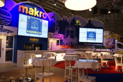 Stoisko targowe Makro CC z brandingiem Select HORECA prezentowane na targach Eurogastro, wyposażone w ekrany, stoliki ze stołkami oraz elementy dekoracyjne w nowoczesnym oświetleniu. projekt i nadzór Tatjana Kobuszewska trksystem.com