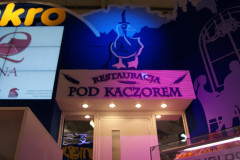 Wejście do restauracji z napisem Restauracja Pod Kaczorem pod ilustrowaną postacią kaczki na niebiesko-fioletowej ścianie - przypomina żywe wystawy w targi Eurogastro lub stoisko targowe Makro CC. projekt i nadzór Tatjana Kobuszewska trksystem.com