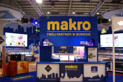 Stoisko targowe Makro CC na targach Eurogastro to niebiesko-żółta ekspozycja z napisem Twój partner w biznesie i zdjęciami produktów, ustawiona w krytej hali wystawienniczej. projekt i nadzór Tatjana Kobuszewska trksystem.com