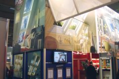 Podwójne stoisko z wyłącznikiem banerami prezentującymi okno dachowe i świetliki. Na stoisku są oprawione certyfikaty, kontrolery okien oraz materiały informacyjne. Odwiedzający aktywnie rozmawiają z ekspozycją. projekt i nadzór Tatjana Kobuszewska trksystem.com