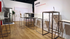 Nowoczesny showroom z drewnianą podłogą wyposażony jest w wysokie metalowe stoły i białe stołki barowe. Po lewej stronie znajduje się lodówka ze stali nierdzewnej. Na tylnej ścianie widnieje napis "smeg" i "The beauty of performance". Schematy i grafiki szkła zdobią ściany. projekt i nadzór Tatjana Kobuszewska trksystem.com