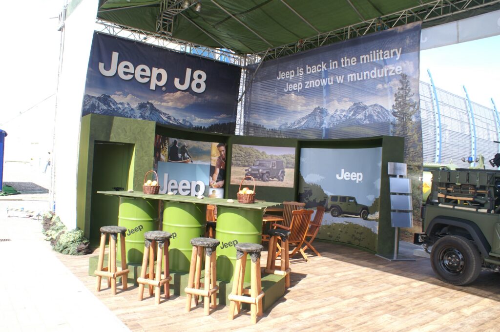 Na stoisku wystawienniczym znajduje się duży branding Jeep J8, zielone ściany z górską grafiką oraz drewniane stoły z taboretami marki Jeep. Na stoisku Jeepa na targach MSPO, Jeep w stylu wojskowym i dwujęzyczne banery prezentują wojskowe dziedzictwo Jeepa. projekt i nadzór Tatjana Kobuszewska