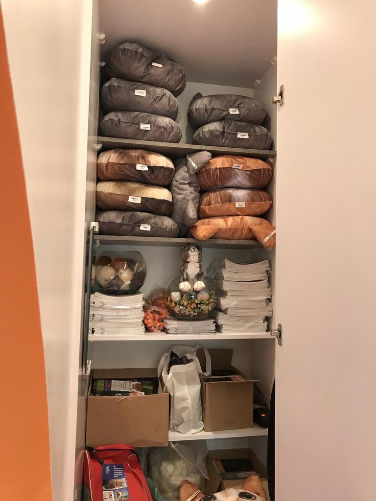 Szafa na zapleczu stoiska targowego kryje starannie ułożone koce, pliki, papiery, torby i pudełka. Dekoracyjna figurka sowy stoi wśród schowków, wszystko ciepło oświetlone. projekt i nadzór Tatjana Kobuszewska trksystem.com