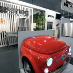 Stoisko Smeg na targach EuroGastro prezentuje urządzenia SMEG Foodservice. Czerwona lodówka SMEG, stylizowana na przód zabytkowego Fiata 500, wyróżnia się wśród przemysłowych urządzeń kuchennych i nowoczesnych logo SMEG. projekt i nadzór Tatjana Kobuszewska trksystem.com