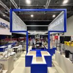 Stoisko targowe z niebiesko-białym brandingiem Technica Group zawiera urządzenia kuchenne, przybory kuchenne i naczynia kuchenne wyeksponowane na ladach. Niebieskie ramki nad głową i wiszące banery z logo Technica podkreślają nowoczesny design stoiska targowego. projekt i nadzór Tatjana Kobuszewska trksystem.com