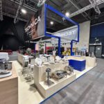 Stoisko targowe dla Technica Group prezentuje sprzęt gastronomiczny, taki jak naczynia do smażenia, tace do serwowania i talerze. Biało-niebieskie stoisko zawiera próbki produktów na ladach i duży napis TECHNICA zawieszony pod oświetleniem przemysłowym. projekt i nadzór Tatjana Kobuszewska trksystem.com