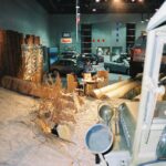 Wewnętrzny eksponat przedstawia pustynną scenę z piaskiem, suchymi roślinami, drewnianymi kłodami, szklaną gablotą i wojskowym jeepem (willys) na pierwszym planie. projekt i nadzór Tatjana Kobuszewska trksystem.com