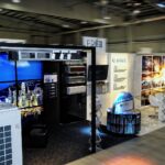 Nowoczesne stoisko wystawiennicze w Ptak Warsaw Expo prezentuje urządzenia HVAC, kanały i systemy wentylacyjne. Banery z napisem "GREE". Oświetlenie dekoracyjne, obrazy miasta i stoiska produktowe wypełniają przestronną, dobrze oświetloną halę. projekt i nadzór Tatjana Kobuszewska trksystem.com