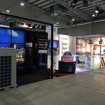 Nowoczesne stoisko wystawiennicze na Międzynarodowych Targach HVAC, Ptak Warsaw Expo obejmuje branding Gree, duże jednostki HVAC, wyświetlacze cyfrowe i podświetlaną grafikę. Przestrzeń obejmuje część wypoczynkową ze stołkami i stołami na polerowanej betonowej podłodze. projekt i nadzór Tatjana Kobuszewska trksystem.com