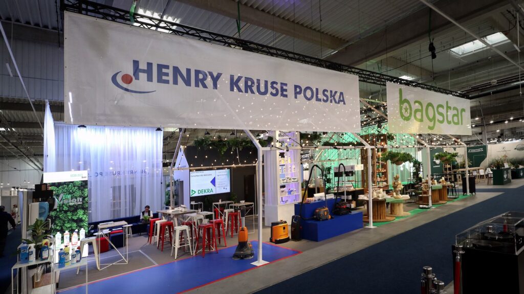 Ascetyczna, szaro-niebieska ekspozycja Henry Kruse na Eurogastro zawiera duże banery Henry Kruse Polska i bagstar, eksponując produkty do profesjonalnego sprzątania na stołach i półkach, z czerwonymi stołkami i dekoracyjnymi roślinami w całym sklepie. projekt i nadzór Tatjana Kobuszewska trksystem.com