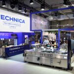 Nowoczesne stoisko targowe na Eurogastro i Ptak Warsaw Expo z jasnym oświetleniem eksponuje markę TECHNICA i hasło "To tworzy profesjonalną kuchnię". Urządzenia ze stali nierdzewnej są starannie rozmieszczone w niebiesko-białej przestrzeni wystawienniczej. projekt i nadzór Tatjana Kobuszewska trksystem.com