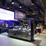 Nowoczesne Stoisko Technica na Eurogastro w Ptak Warsaw Expo - 70 m² z niebiesko-białym brandingiem oferuje przemysłowe wyposażenie kuchni, cyfrowe ekrany z logo Technica i jasne oświetlenie w czystej, zorganizowanej przestrzeni do prezentacji urządzeń. projekt i nadzór Tatjana Kobuszewska trksystem.com