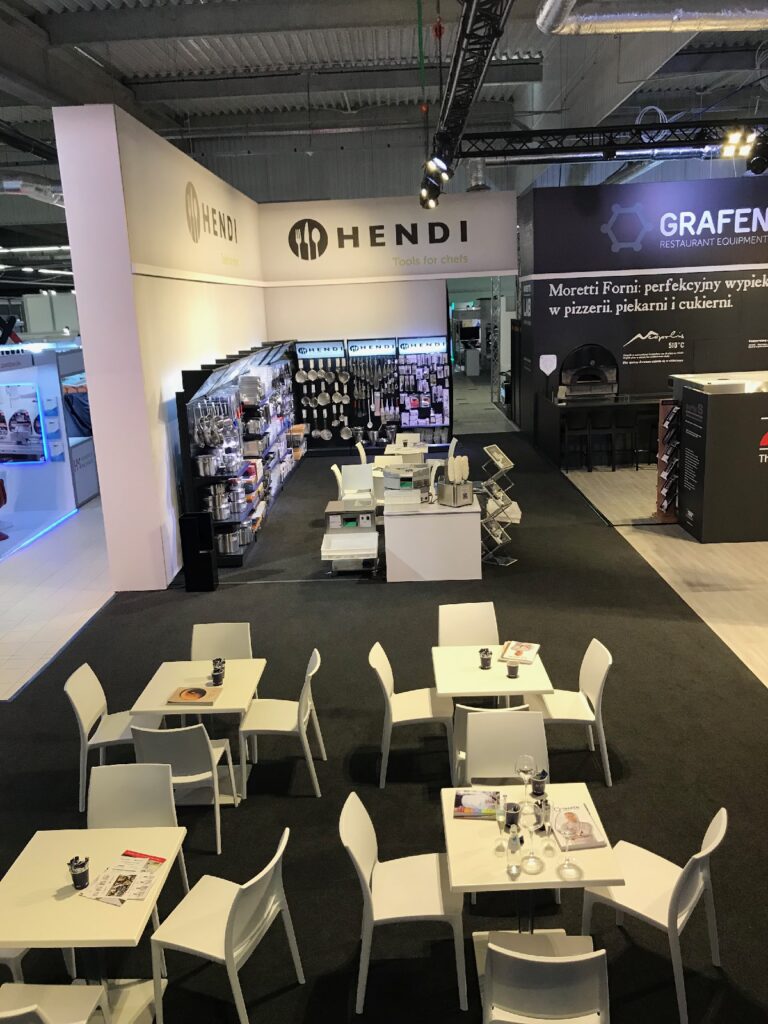 Na stoisku targowym na półkach i ścianach prezentowane są przybory kuchenne marki Hendi; zajmuje ono przestronną powierzchnię 414 m² w hali F centrum PTAK Warsaw