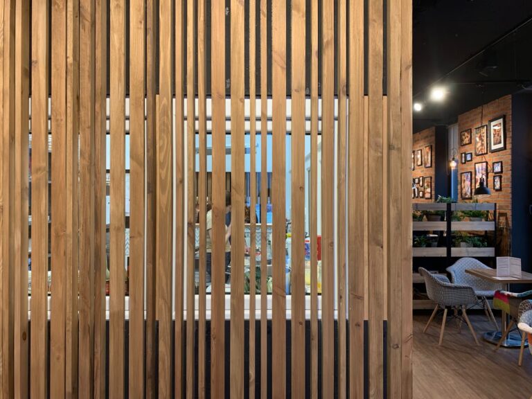 Ażurowy ekran z pionowych drewnianych lameli oddzielający salę konsumpcyjną od zaplecza kuchennego w bistro Przystanek Piekarnia w Piasecznie. projekt i nadzór Tatjana Kobuszewska trksystem.com
