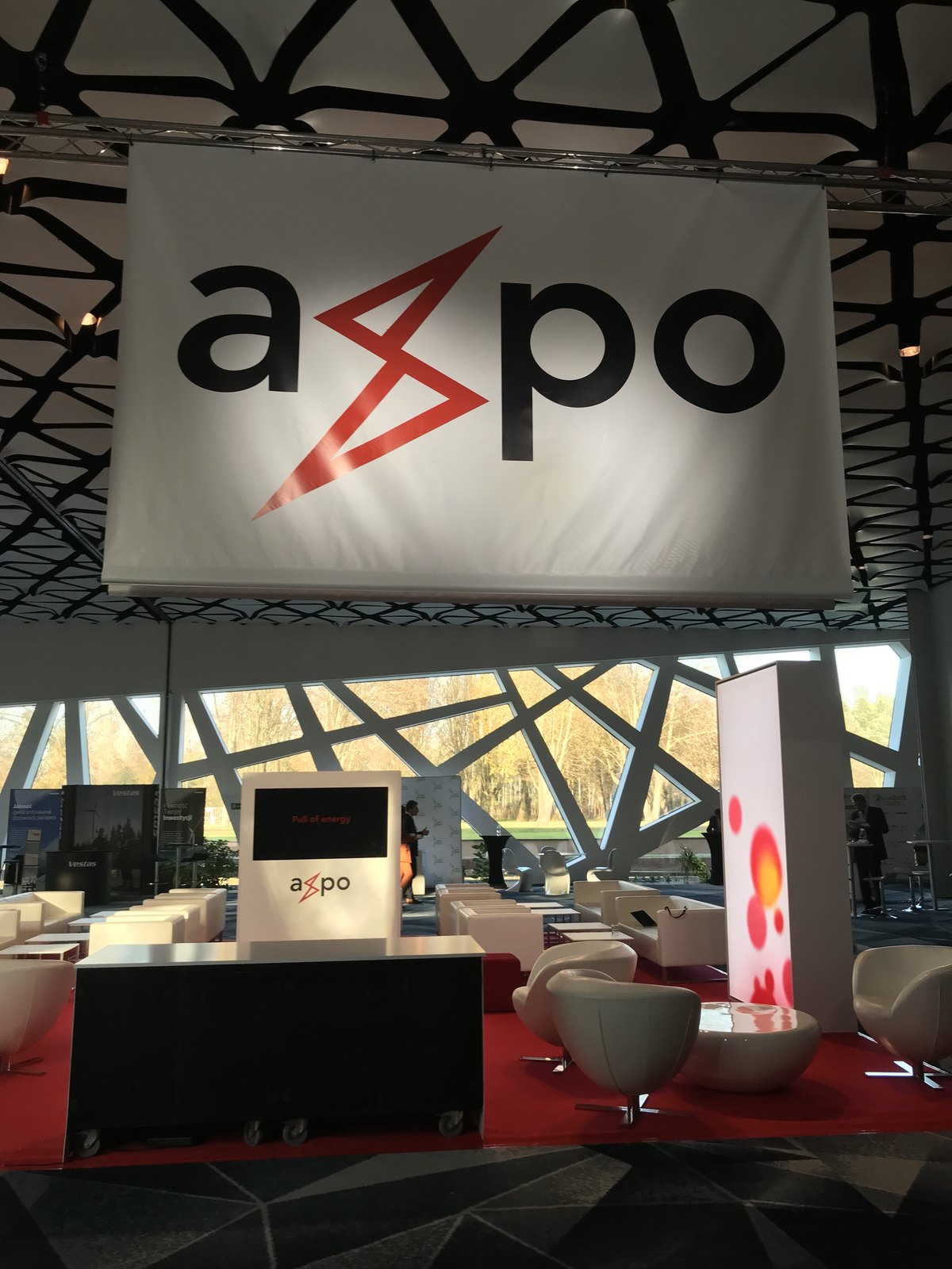 Stoisko Axpo z podwieszanym logo i ekranami, przy przejściu konferencyjnym