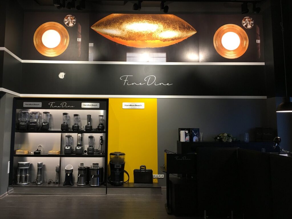 Ciemne wnętrze salonu z podświetlanym fryzem, regałami z porcelaną i lampami nad stołami