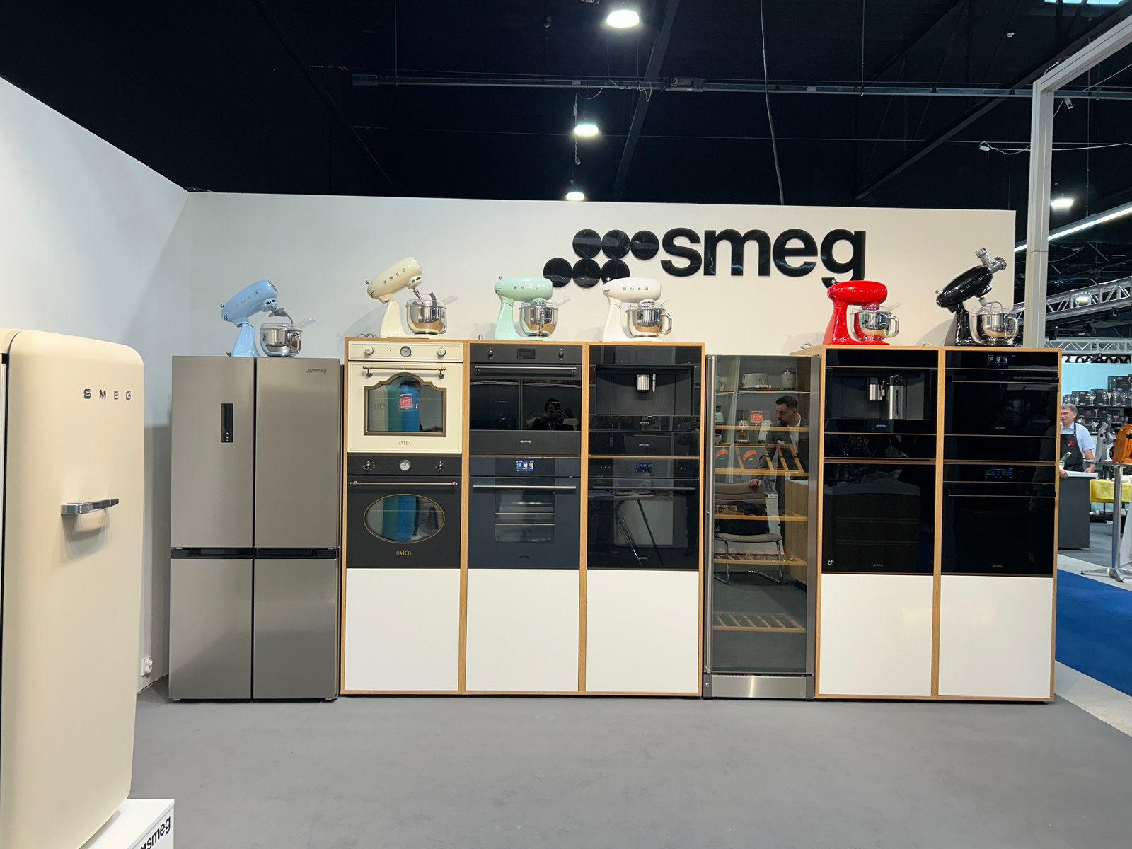 Ściana z piekarnikami, ekspresem i lodówką w zabudowie, pod logo smeg
