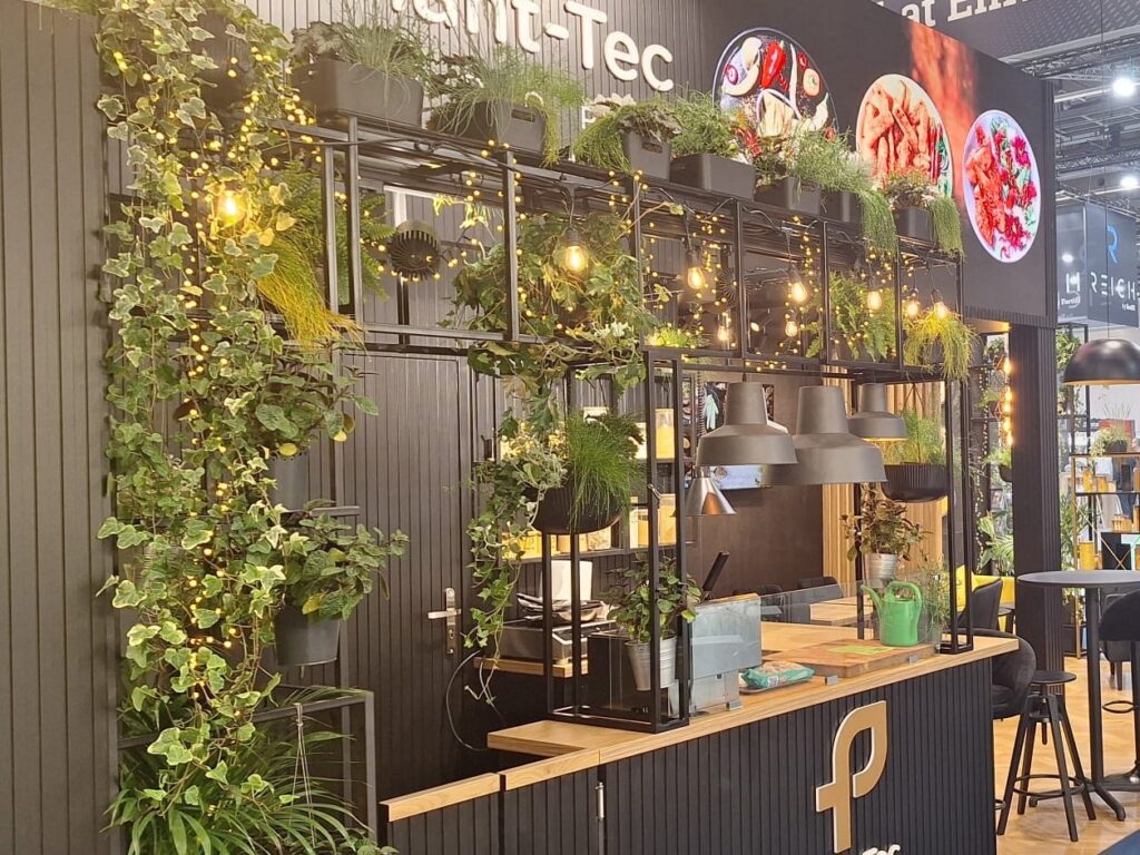 Stoisko Plant-Tec Europe na targach IFFA we Frankfurcie: czarna ściana z ogrodem wertykalnym, lampy i lada barowa. Projekt i nadzór Tatjana Kobuszewska, TRK System